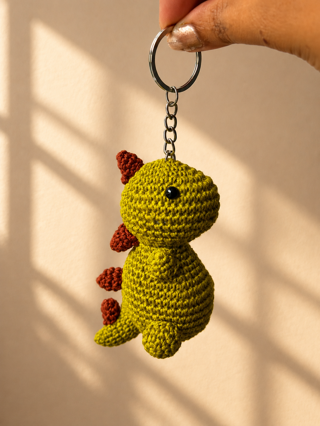 Green crochet dinosaur keychain side view