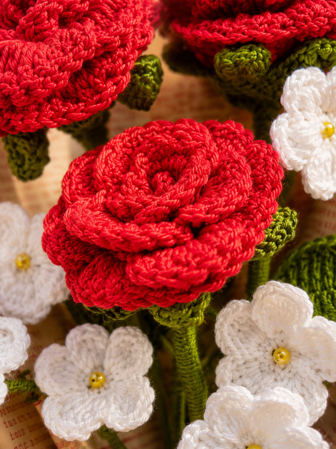 Close-up detail of handmade crochet red roses and white flowers by Rubber Band