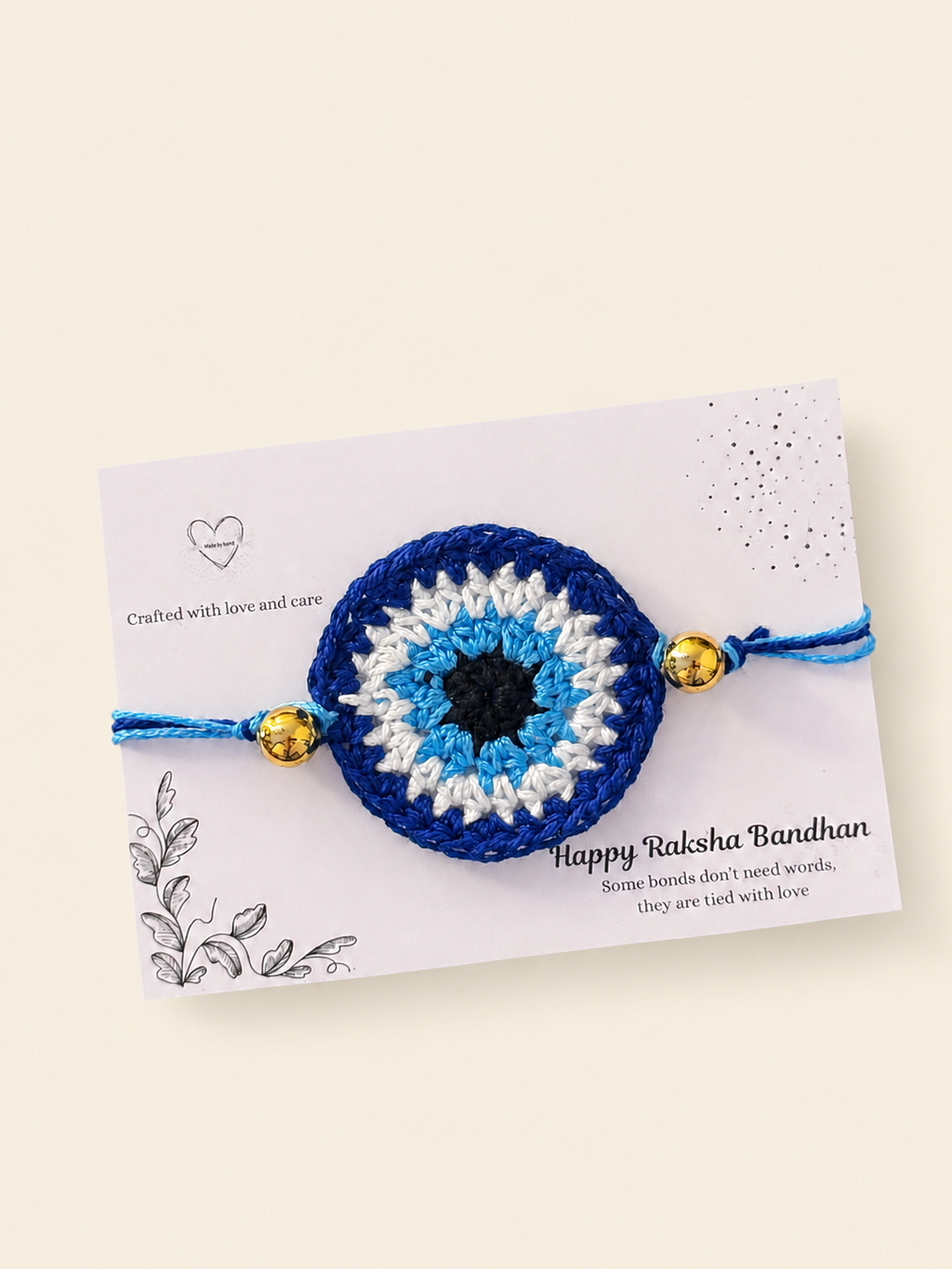 Handmade blue nazar crochet rakhi with gold-tone bead accents on a Raksha Bandhan card