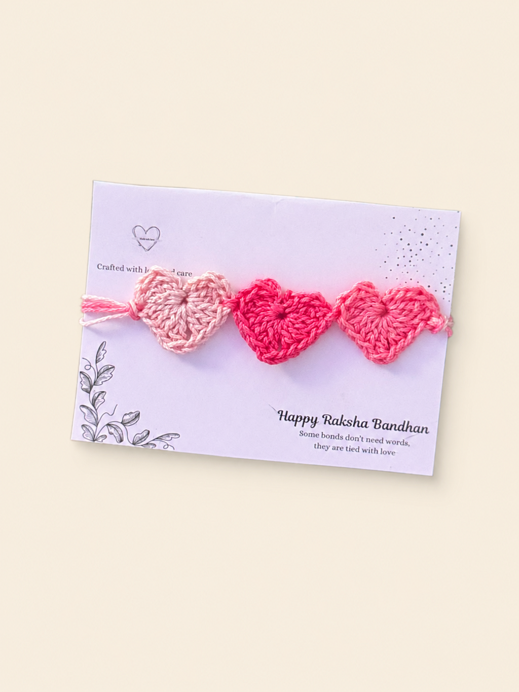 Handmade crochet Rakhi with three pink hearts on a Raksha Bandhan presentation card