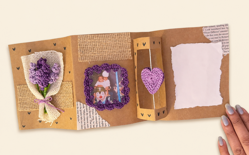 Open handmade Rakhi memory scrapbook with crochet flower bouquet, photo frame, hanging heart and message space
