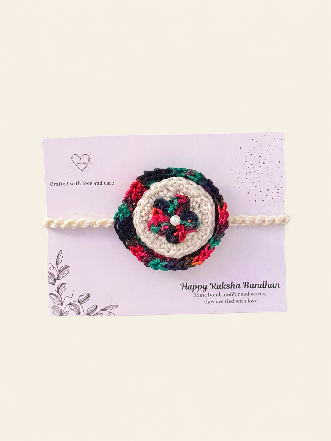 Handmade multicolour floral crochet rakhi with an ivory centre and cream ties on a Raksha Bandhan presentation card