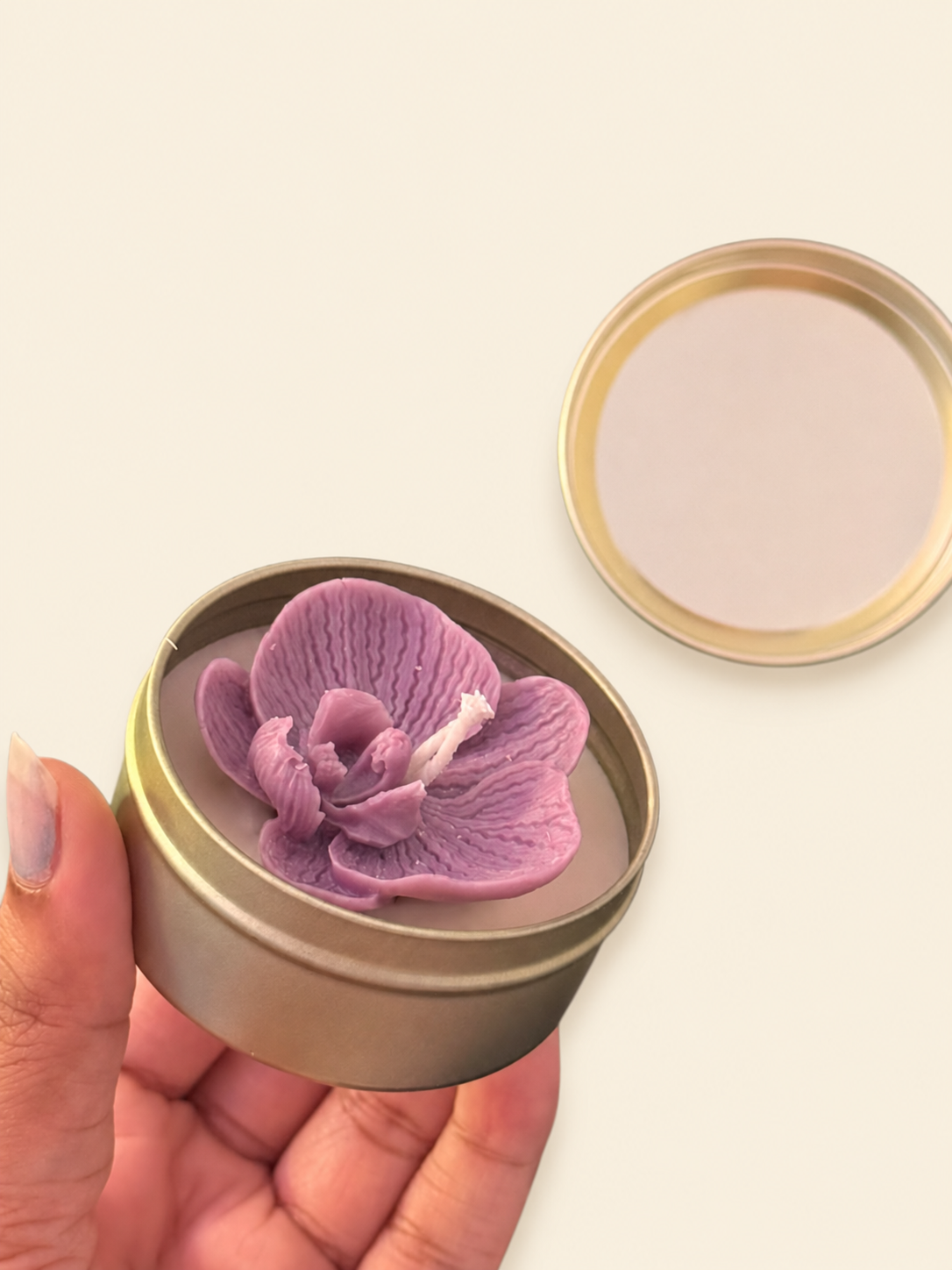 Purple orchid-shaped candle in a reusable round metal tin with lid