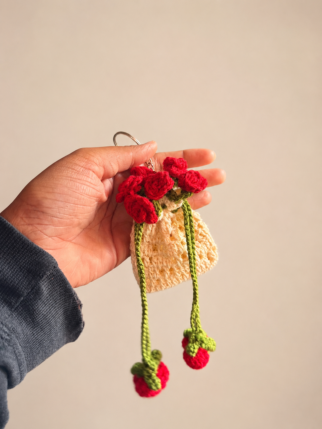 Handmade crochet rose bouquet bag charm held in hand