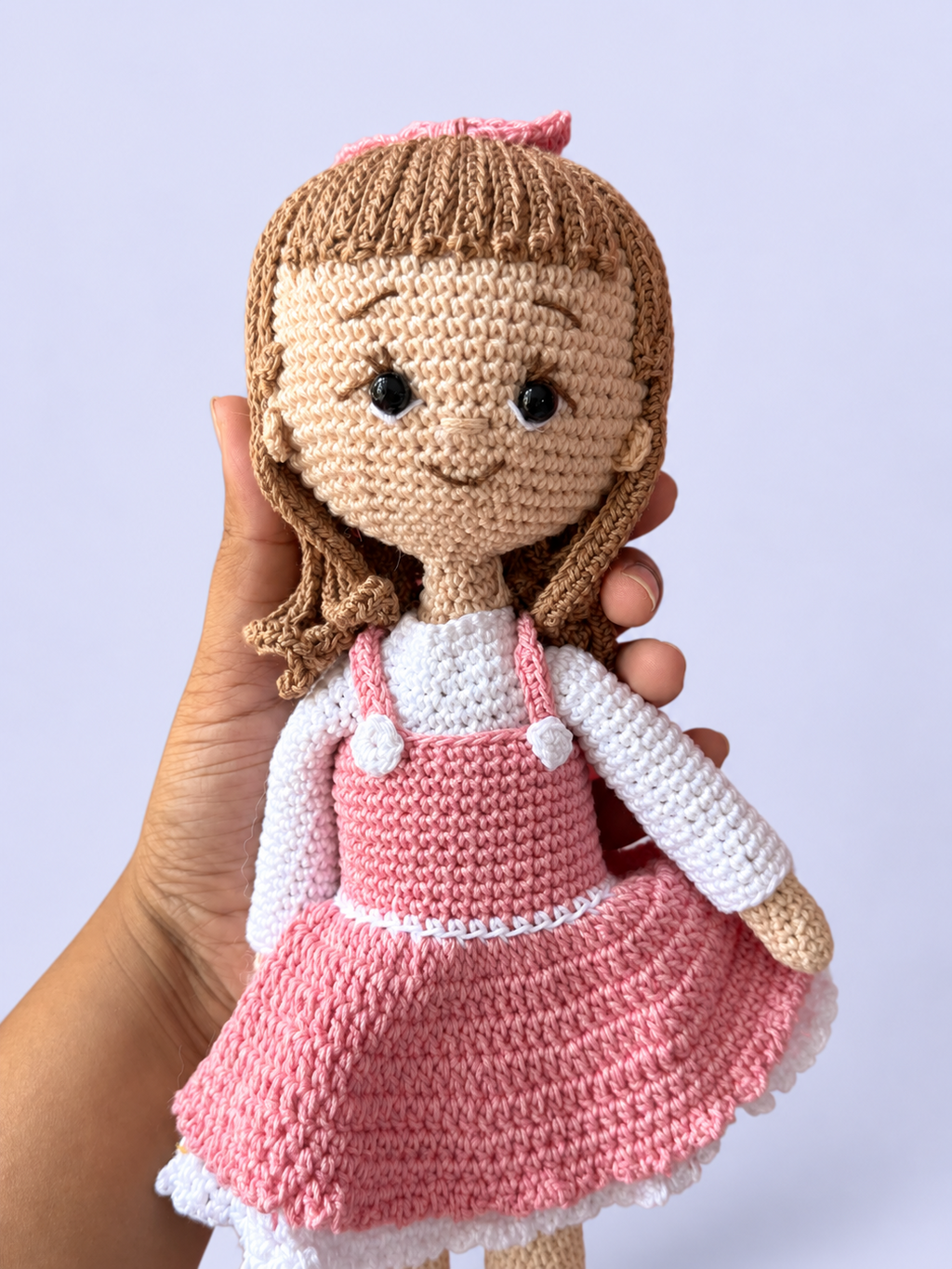 Rosie the Doll in pink dress held in hand for scale