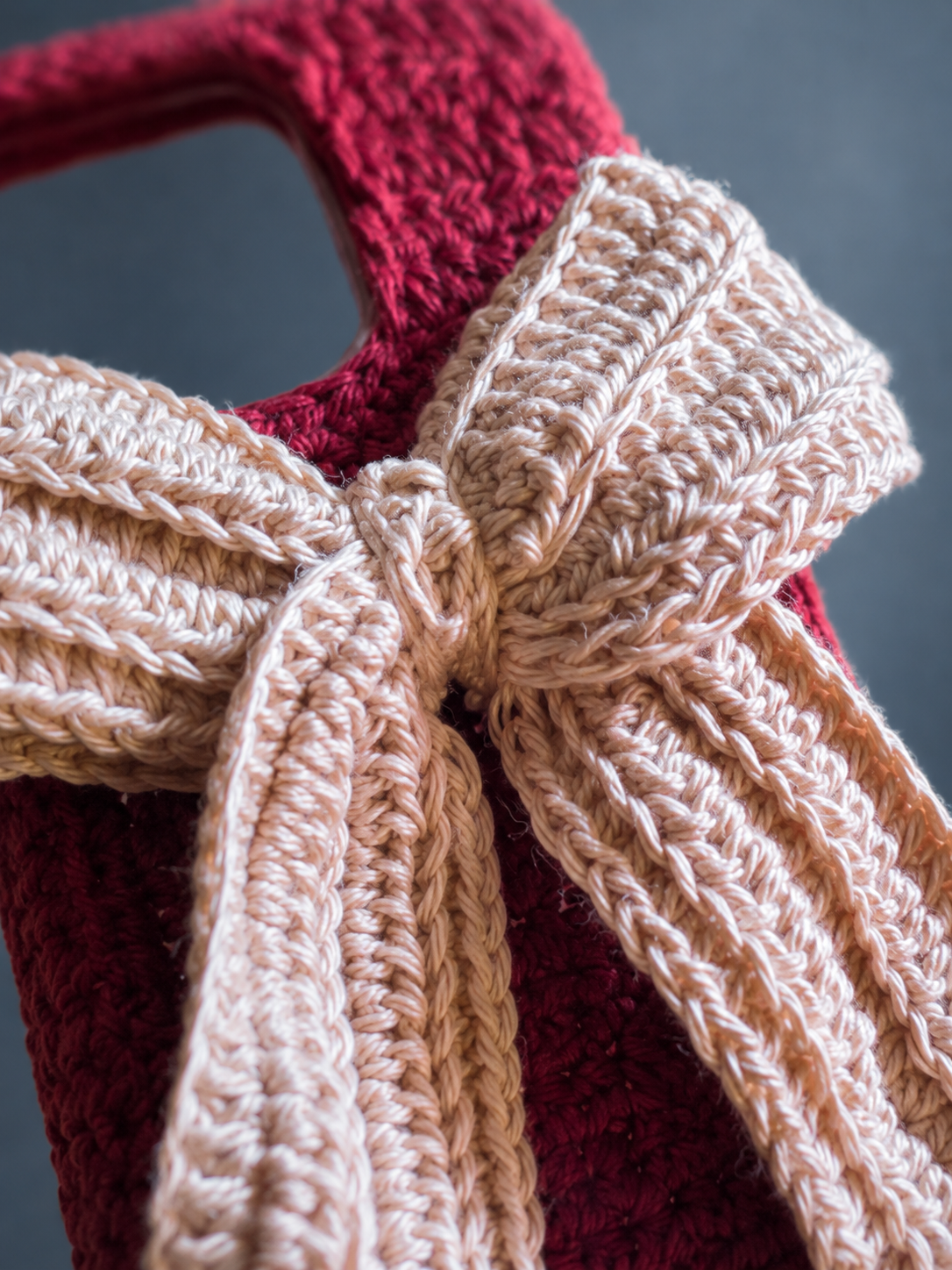 Close-up of the oversized ivory crochet bow and burgundy phone cover stitching