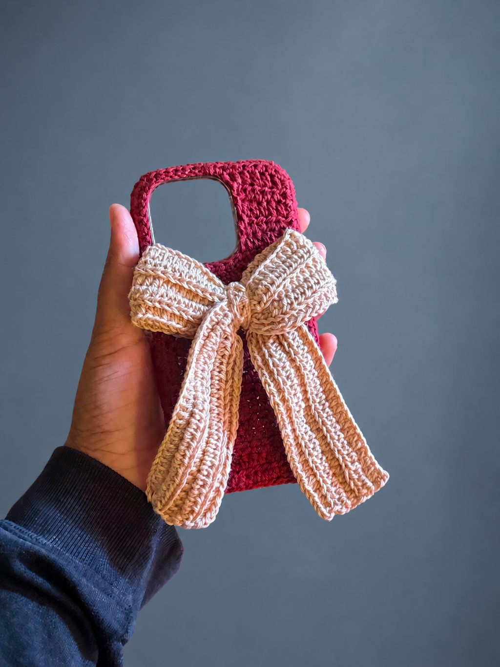 Handmade burgundy crochet phone cover with an oversized ivory bow