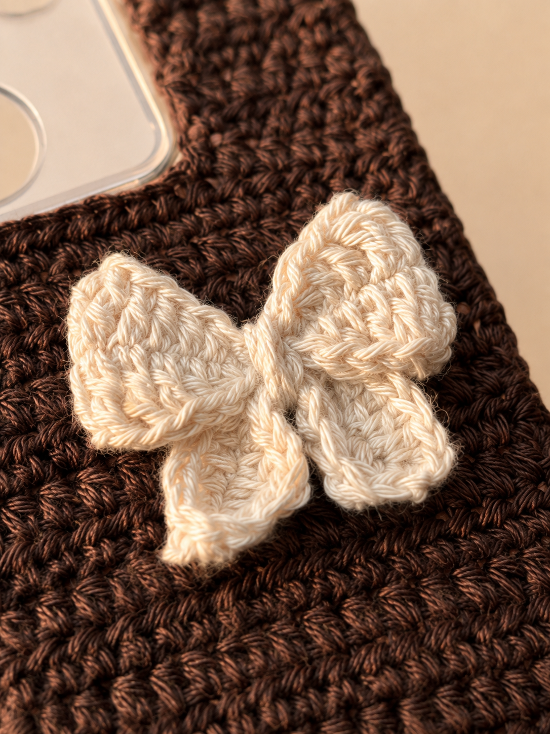 Close-up of the ivory crochet bow and brown phone cover stitching
