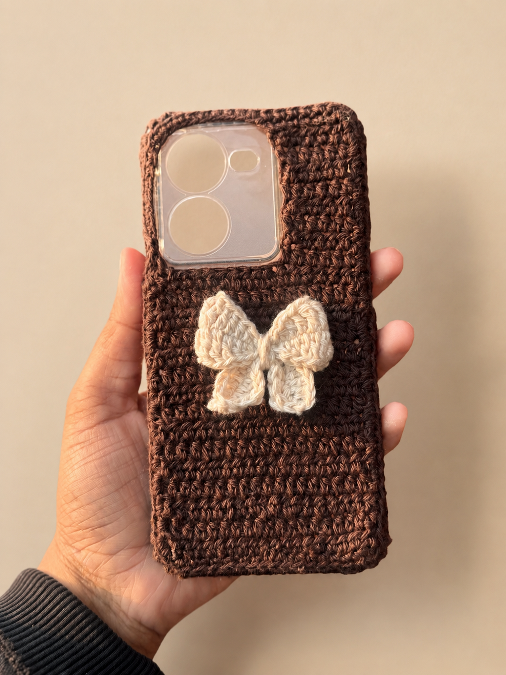 Handmade brown crochet phone cover with a small ivory bow