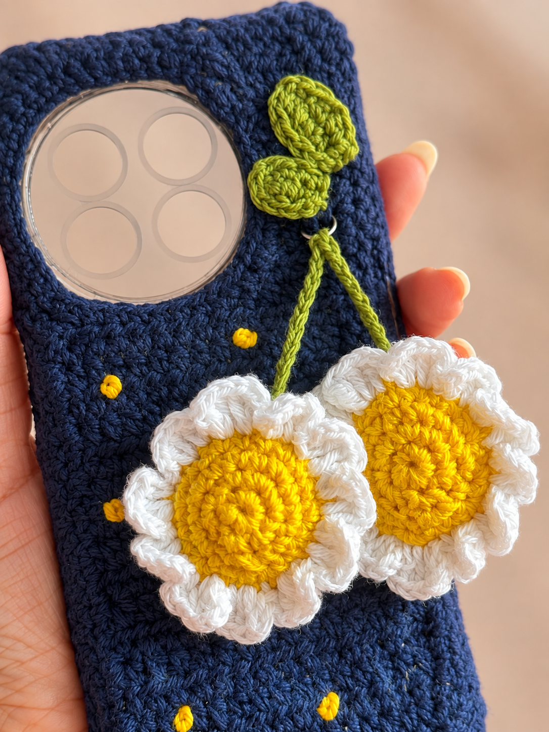 Close-up of white and yellow crochet daisies on a navy phone cover