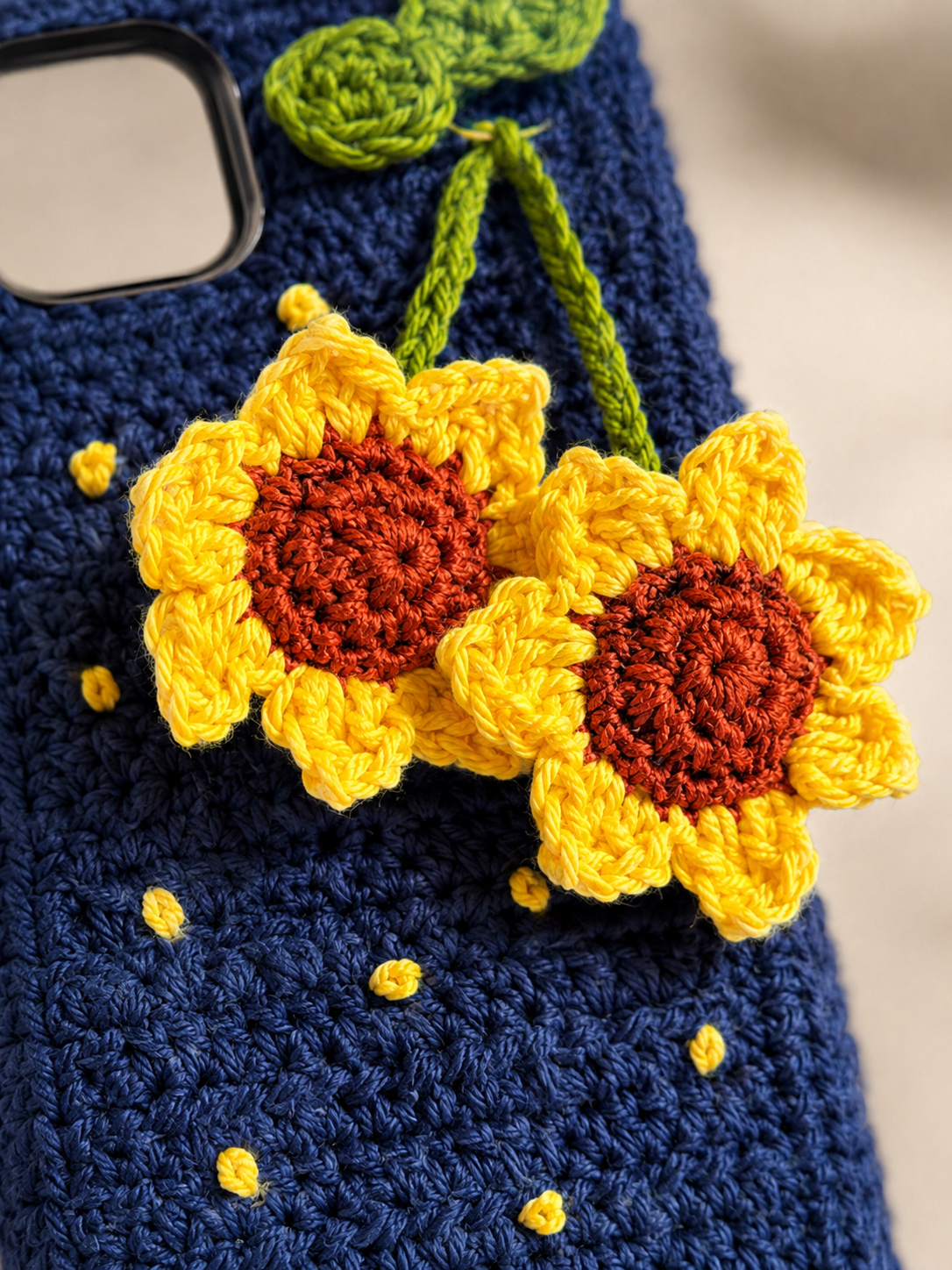 Close-up of crochet sunflower details on a navy phone cover