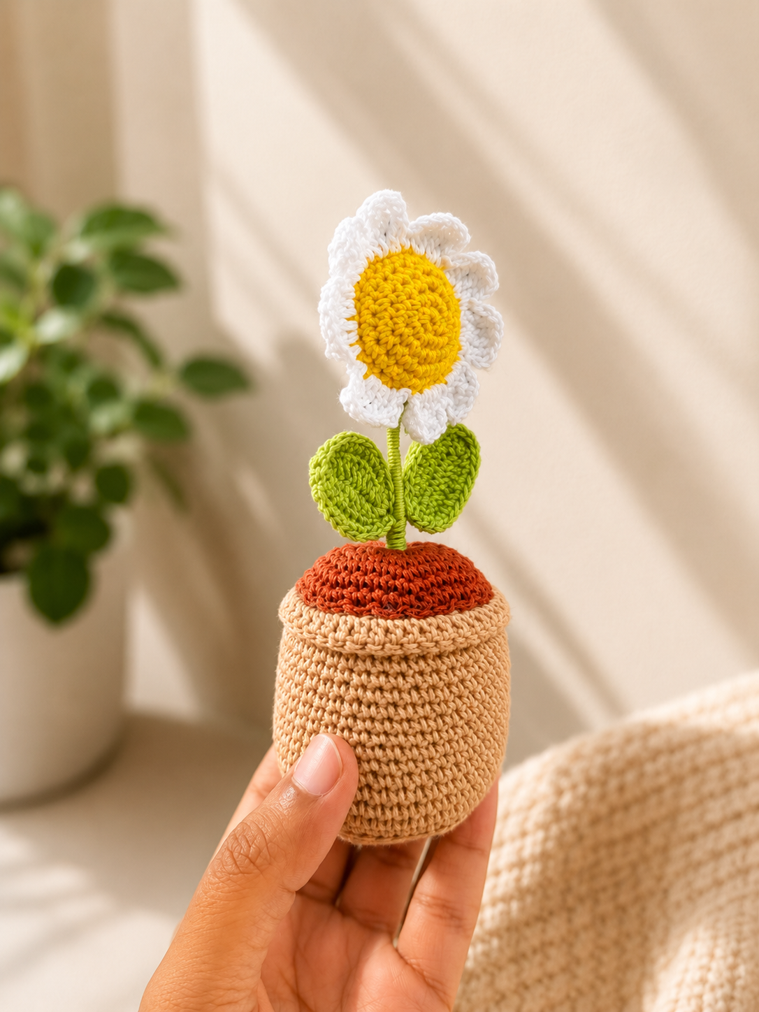 Handmade crochet daisy flower pot held in hand, angled side view