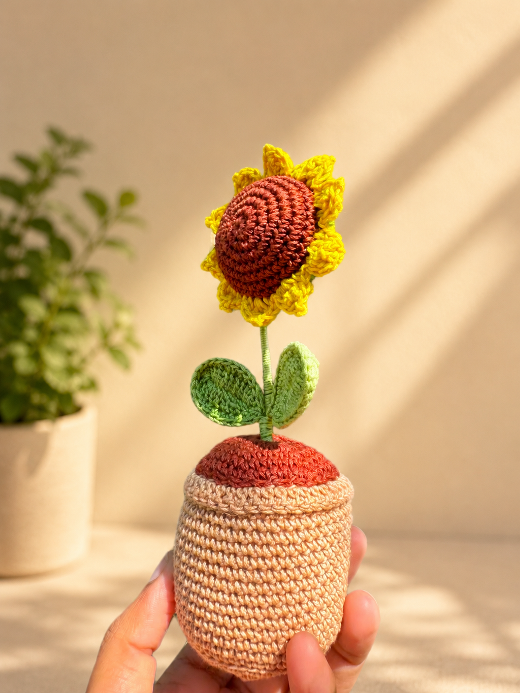 Handmade crochet sunflower flower pot held in hand, angled side view