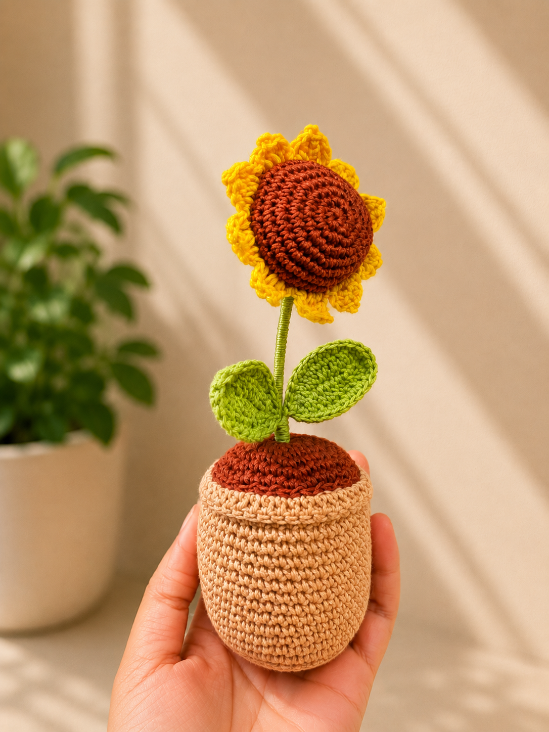 Handmade crochet sunflower flower pot held in hand, three-quarter view