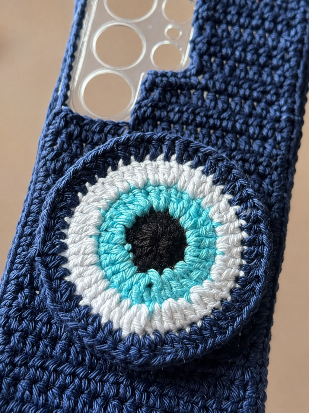Close-up of raised turquoise white and navy crochet evil eye design