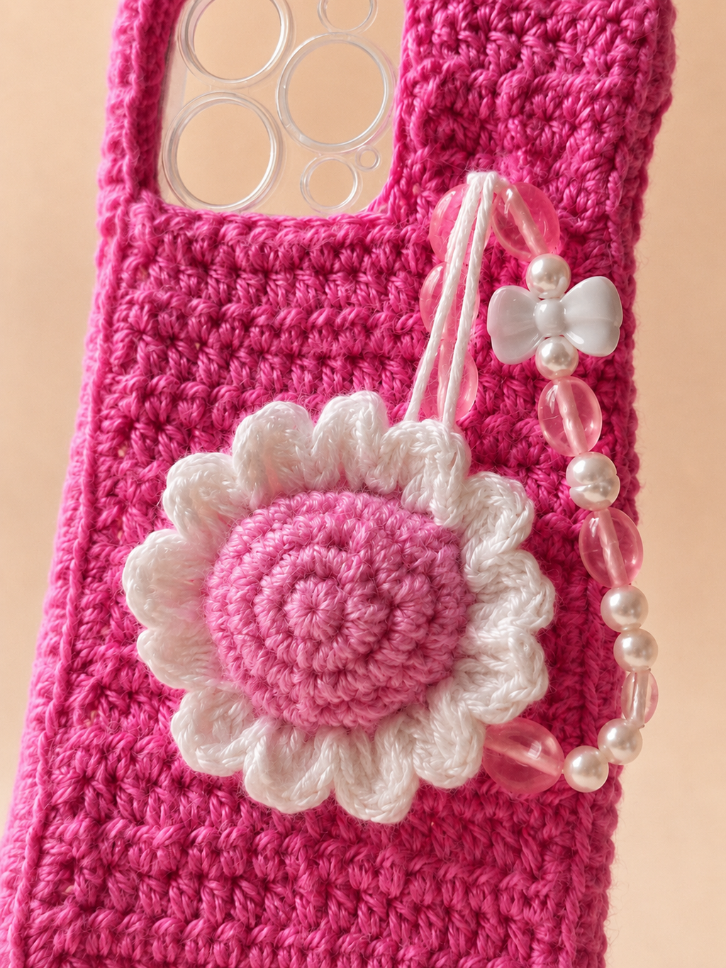Close-up of pink and white crochet daisy charm with pearl and bow bead strap