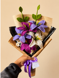 Handmade purple and ivory crochet lily bouquet held in hand with gift-ready wrapping