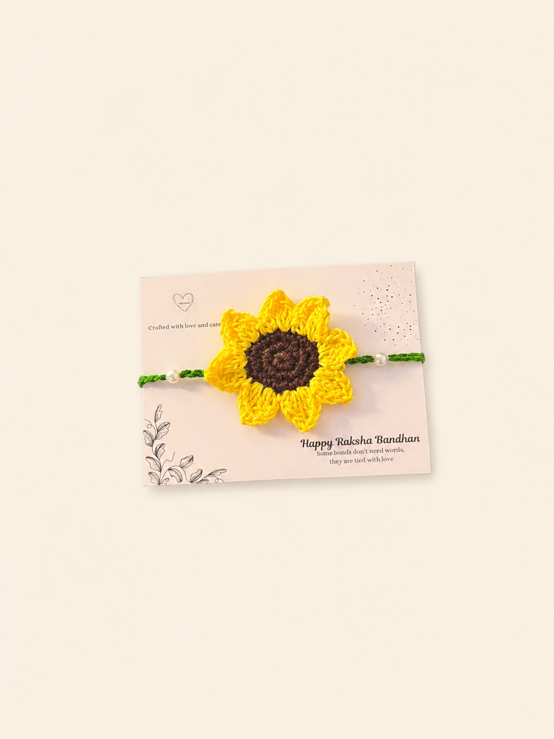 Handmade yellow sunflower crochet rakhi with green ties and pearl accents on a Raksha Bandhan card